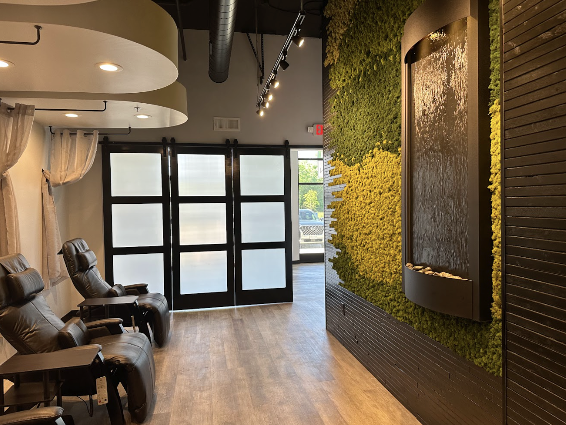 A waiting room with chairs and a wall covered in moss.